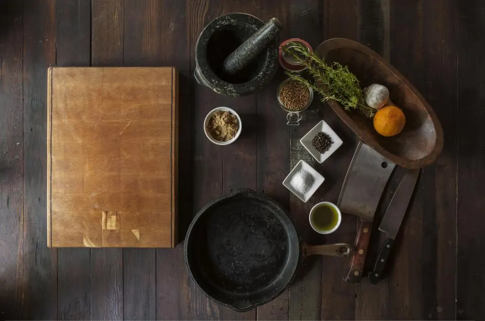 Butcher block, cleaver and seasoning laid out on a dark prep table
